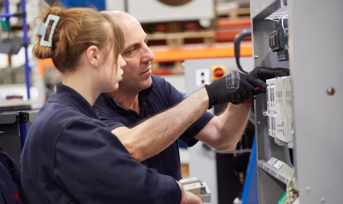 Young engineer receiving training from KMF employee.
